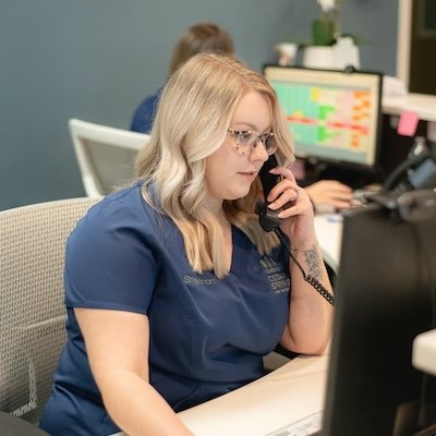 Receptionist at a dentist office talking on the phone.